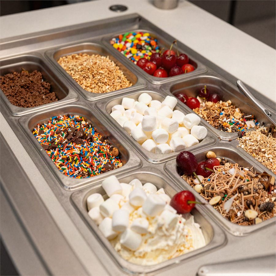Topping bins filled with sprinkles, jimmies, nuts and candy pieces.